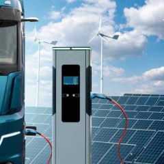 Electric truck with charging station on a background of solar panels and wind turbines. Concept