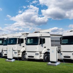 Row of electric semi trucks at charging stations for electric vehicles